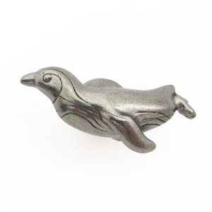 May include: A pewter-colored seal figurine, depicted in a swimming pose. The sculpture has detailed lines and a smooth finish, with a small tail and flippers. The seal is set against a white background.