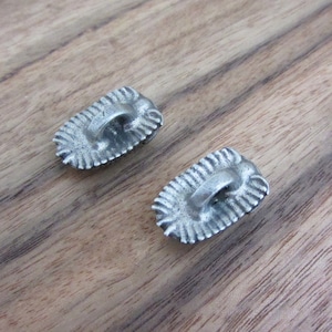 May include: Two silver-toned metal buckles with a decorative design. Each buckle has a loop for attaching to a strap or belt.