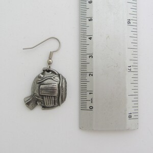 May include: Silver tone fish shaped earrings with a detailed design. The earrings are approximately 2 cm in length.