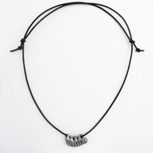 May include: A black cord necklace featuring a silver-toned pendant shaped like a sloth. The sloth pendant has detailed etched lines and is suspended from the adjustable cord. The necklace is displayed against a white background.