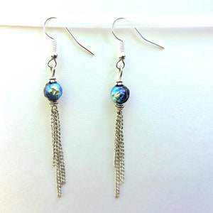 May include: A pair of silver dangle earrings with a blue and black iridescent bead and a silver chain tassel.