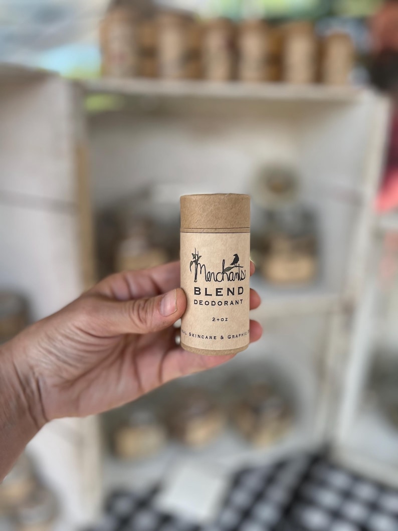 K&ouml;nnte beinhalten: Ein zylindrischer Deodorant-Stick mit einer braunen Pappr&ouml;hre und Kappe. Das Etikett lautet "Merchants Blend Deodorant" mit einer kleinen Vogelgrafik. Das Produkt ist 57g und tr&auml;gt die Aufschrift "Natural Skincare & Graphics".