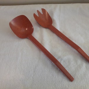 May include: A set of two brown wooden salad serving utensils. The set includes a spoon and a fork.
