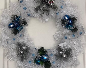 White wreath embellished with turquoise and silver decorations and ribbon