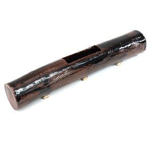 May include: A brown ceramic planter shaped like a log with a black glaze and wood grain pattern. The planter has a rectangular opening for planting and four small gold feet.