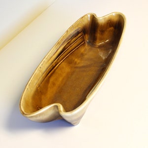 May include: A brown ceramic serving dish with a wavy edge and a slightly textured surface.