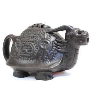 May include: Black ceramic incense burner shaped like a turtle with a dragon head on top. The turtle has a detailed shell with intricate carvings.