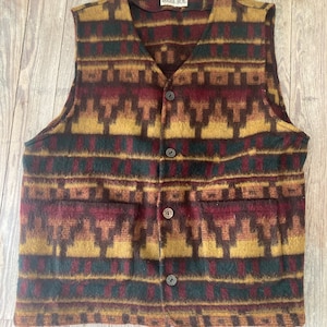 May include: A brown, black, red, and gold patterned vest with a button closure. The vest has two pockets and a label that reads "Bugle Boy."