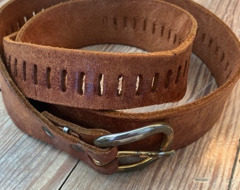 May include: A brown leather belt with a silver buckle and a row of evenly spaced holes along the length of the belt.