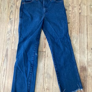 May include: A pair of dark blue denim jeans with a frayed hem.