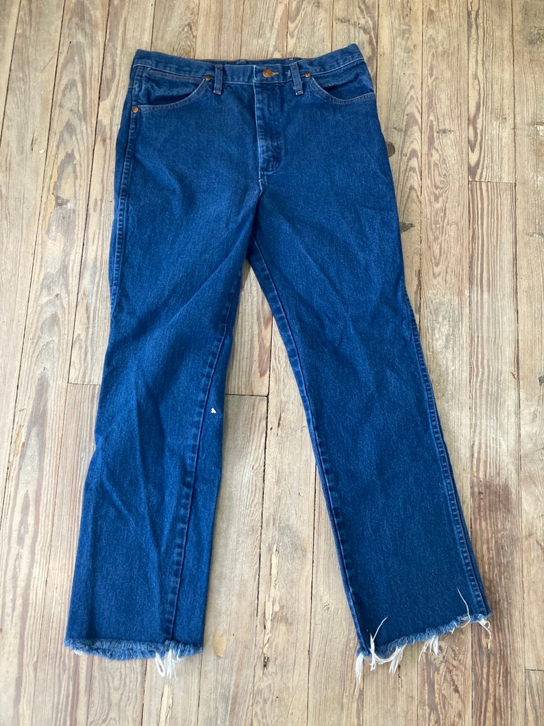 May include: A pair of dark blue denim jeans with a frayed hem.