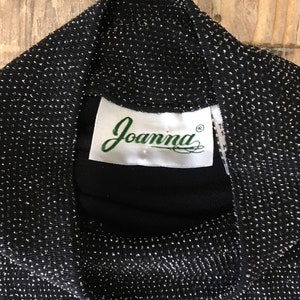 May include: Black sparkly fabric with a white label that says "Joanna" in green cursive lettering.