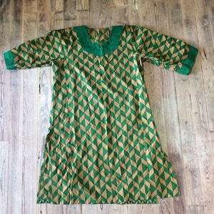 May include: A green and gold geometric patterned tunic with a green collar and short sleeves.