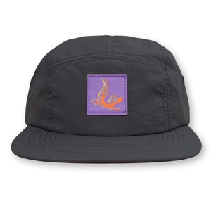 May include: A black 5-panel cap with a purple patch featuring an orange lizard design.