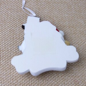 May include: White ceramic Christmas ornament shaped like a snowman with a red hat and a black top hat. The ornament has a white string for hanging.