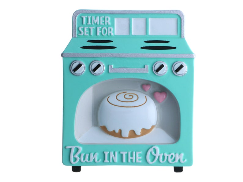 May include: A turquoise blue ceramic oven with a white door and a cinnamon roll inside. The oven has a timer set for and the words "Bun in the Oven" on the front.