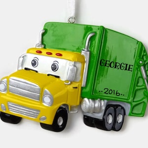 May include: A yellow and green personalized garbage truck Christmas ornament with the name Georgie and the year 2016.