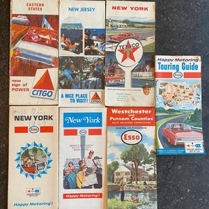 May include: Collection of vintage travel guides and maps, featuring colorful illustrations and text. Guides include "Eastern States," "New Jersey," and "New York," with branding from Citgo, Texaco, and Esso. The guides showcase retro imagery of cars and landscapes.