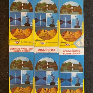 May include: A collection of vintage Sun Oil Company maps. Each map features a blue and yellow design with illustrations of landmarks like the Statue of Liberty and Mount Rushmore. Titles include "Kansas," "Nebraska," and "Eastern United States."