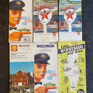 May include: A collection of vintage travel maps and brochures. The brochures feature colorful illustrations and text, including the states of Indiana, Ohio, and Wisconsin. The maps are from the 1960s and include advertisements for gas stations and local attractions.