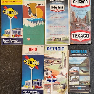 May include: A collection of vintage travel maps and brochures, featuring iconic gas station brands like Sunoco, Mobil, and Texaco. The maps showcase destinations such as Illinois, Ohio, Detroit, and Michigan, with vibrant colors and retro designs.