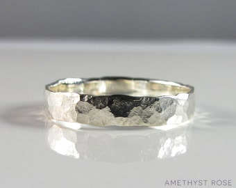 May include: A silver hammered band ring. The ring is made of a smooth, polished metal and has a textured, hammered finish.