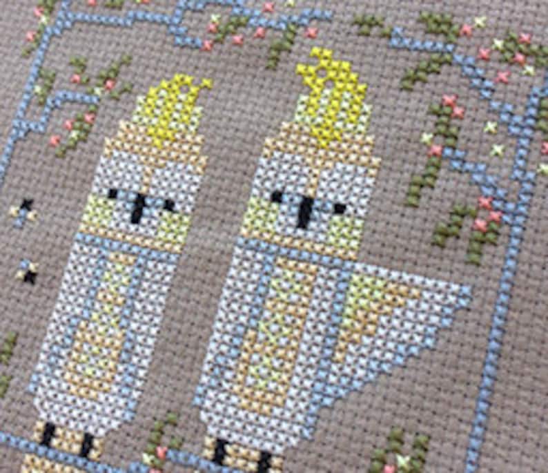 May include: Cross stitch pattern featuring two yellow-crested cockatoos perched on a branch with pink flowers.