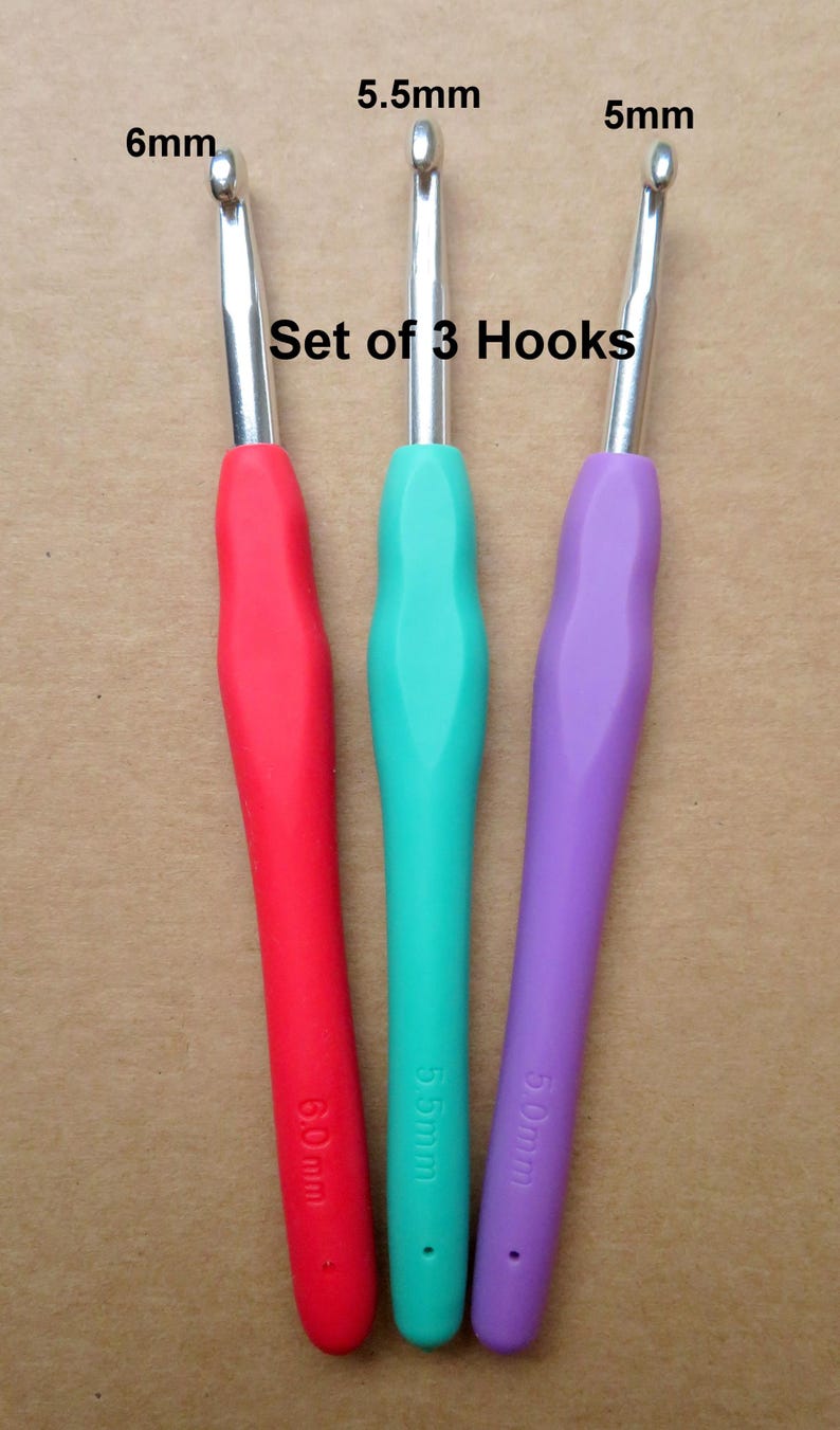 May include: Set of three crochet hooks with colored handles. The hooks are 6mm, 5.5mm, and 5mm. The handles are red, teal, and purple. The text "Set of 3 Hooks" is above the hooks.