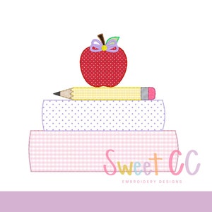 Pode incluir: Um design bordado com uma pilha de livros, um lápis e uma maçã vermelha com um laço. Os livros têm padrões rosa e branco. O texto "Sweet CC Embroidery Designs" está no canto inferior direito.