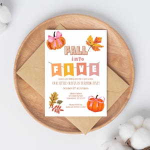 Op de afbeelding: Een verjaardagsuitnodiging met een herfstthema. De uitnodiging bevat oranje pompoenen, herfstbladeren en de tekst "Fall into Five". De uitnodiging staat op een witte achtergrond, met een bruine envelop en een houten bord.
