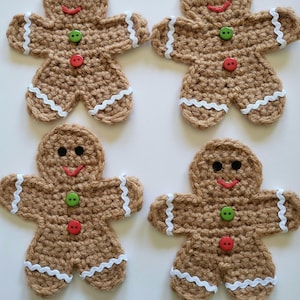 May include: Four handmade crochet gingerbread men. Each gingerbread man is brown with white trim, black eyes, a red smile, and a green and red button. These festive ornaments are perfect for holiday decorating.