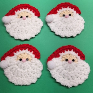 May include: Four crocheted Santa Claus ornaments with white beards and red hats. The ornaments are on a green background.
