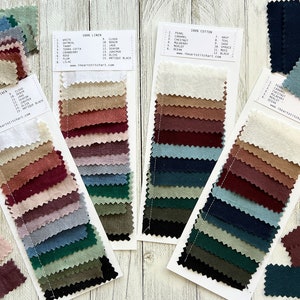 May include: A collection of fabric swatch cards in a range of colours, from cream and beige to deep reds and blues. The cards display fabric samples with colour names and material types, such as 100% linen and cotton. Website details are also visible.