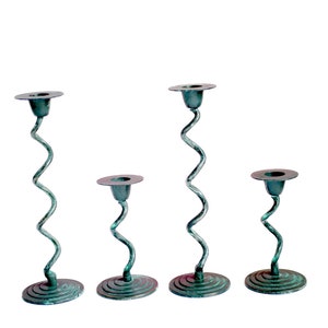 May include: Set of four teal green metal candle holders with a spiral design. The candle holders are different heights.