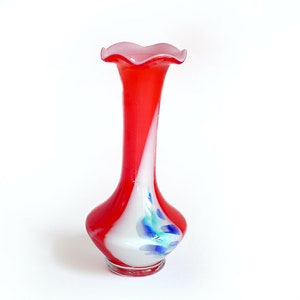 Könnte beinhalten: Eine rote und weiße Glasvase mit einem gekräuselten Rand und einem blauen und weißen Wirbelmuster.