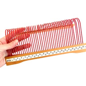 Könnte beinhalten: Ein roter Plastik-Plattenständer mit Holzsockel und nummerierten Fächern. Der Ständer ist mit "Brittix" beschriftet und hat die Nummern 1 bis 40 auf dem Sockel.