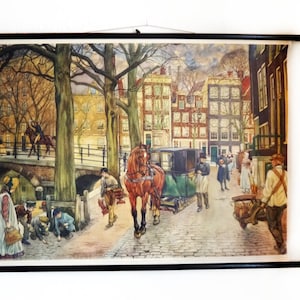 Könnte beinhalten: Ein Vintage-Lehrposter, das eine Pferdekutsche in einer holländischen Stadtstraße zeigt. Das Poster zeigt ein braunes Pferd, das eine Kutsche mit schwarzem Verdeck zieht, und mehrere Personen, die auf der Kopfsteinpflasterstraße gehen. Die Gebäude im Hintergrund sind in warmen Farben gemalt, mit roten Ziegeln und gelben Fassaden. Das Poster ist in einem schwarzen Holzrahmen gerahmt.