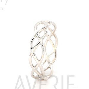 May include: A silver ring with a Celtic knot design. The ring is made of a single piece of metal and has a smooth, polished finish.
