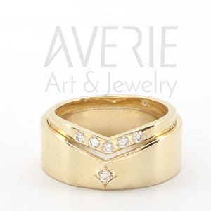 May include: A pair of gold wedding bands with a V-shaped design and small diamonds. The text "AVERIE Art & Jewelry" is visible above the rings.
