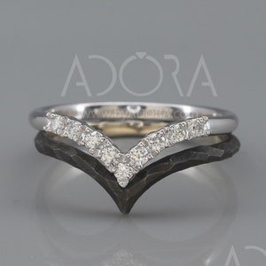 May include: A silver band with a row of small diamonds set in a V-shape. The band is layered on top of a black band with a hammered finish.