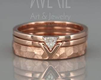 May include: Three rose gold bands with a hammered texture. The top band features a small, triangular diamond.