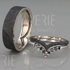 May include: Two black wedding bands with a hammered finish. One band is a simple band, and the other is a V-shaped band with black diamonds.