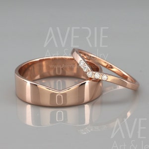 May include: A pair of rose gold wedding bands. The wider band has a V-shaped cut out. The thinner band has a row of small diamonds set in a V-shape.