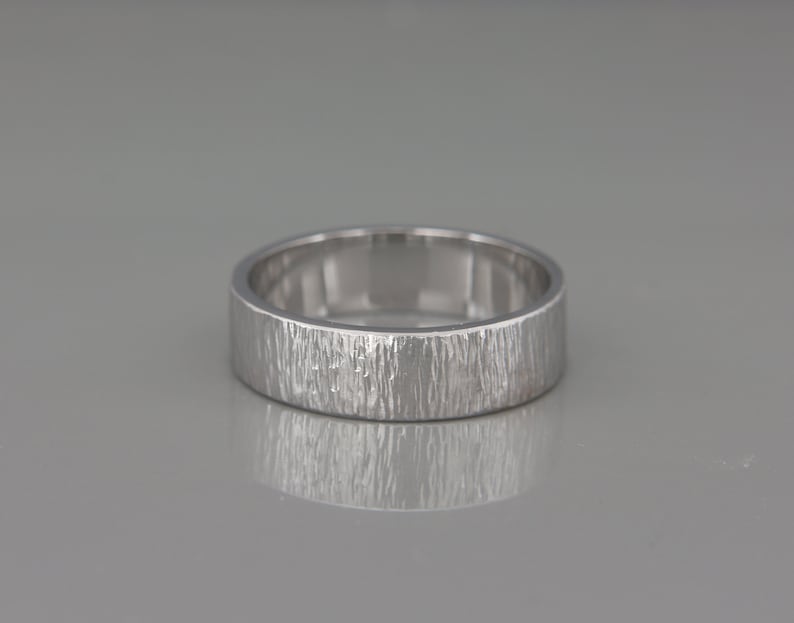 May include: A silver wedding band with a textured, brushed finish.