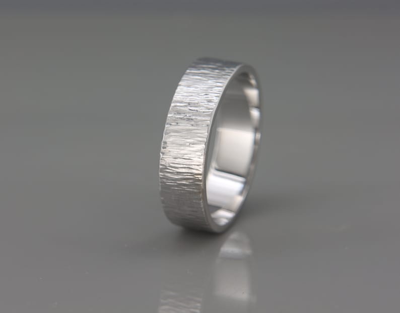 May include: A silver wedding band with a textured finish.