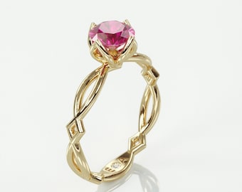 Puede incluir: Un anillo de compromiso de oro con una piedra preciosa rosa engastada en una banda trenzada delicada.