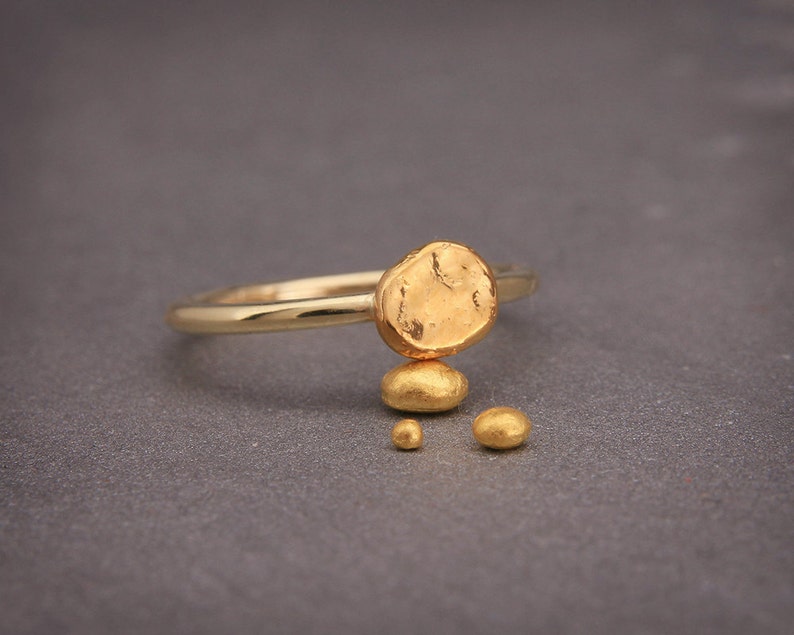 May include: A gold ring with a large, irregular, textured gold nugget on top. Three smaller gold nuggets are below the larger nugget.