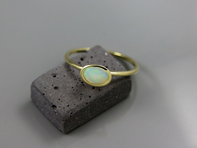 May include: A gold ring with a white opal gemstone set in a bezel setting.