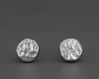 May include: A pair of silver hammered circle stud earrings.
