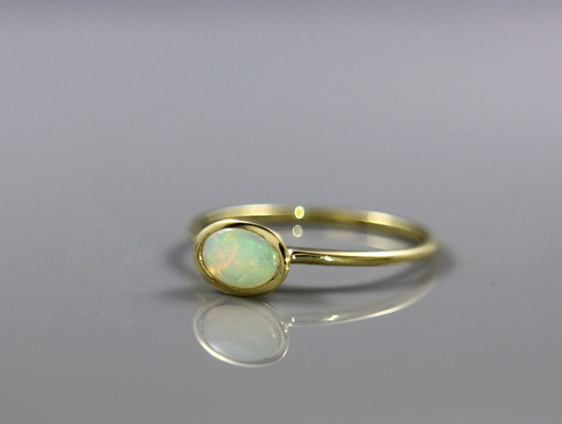 May include: A delicate gold ring with a white opal gemstone. The ring is simple and elegant, perfect for everyday wear.